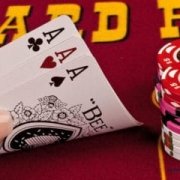 Close-up of a player holding three aces in Three Card Poker with stacks of chips on the table at California Grand Casino