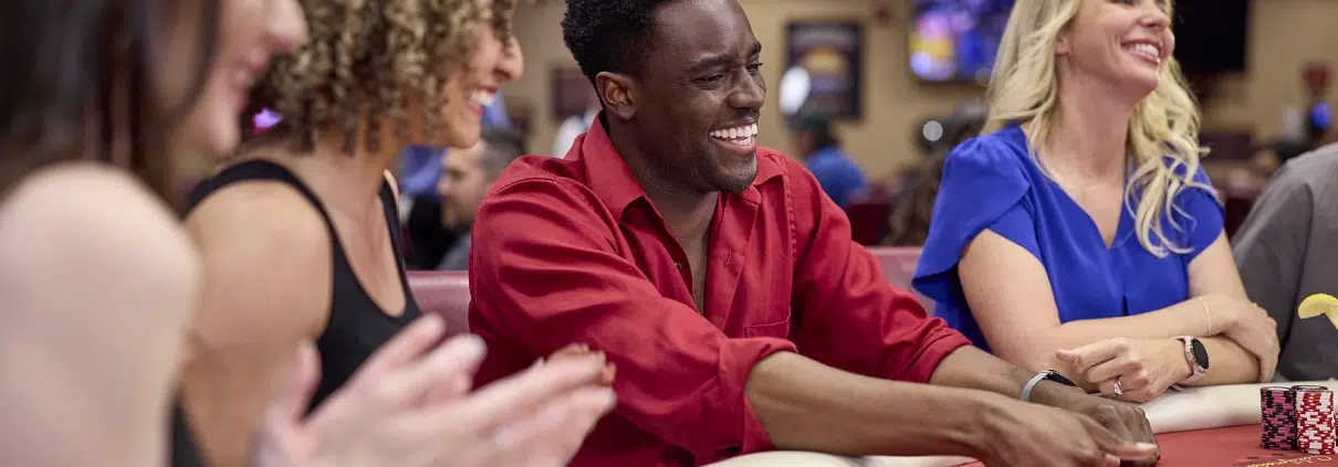 Excited group of players at a poker table in California Grand Casino, showcasing the fun of learning and playing with different poker hand combinations