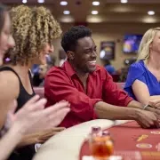 Excited group of players at a poker table in California Grand Casino, showcasing the fun of learning and playing with different poker hand combinations