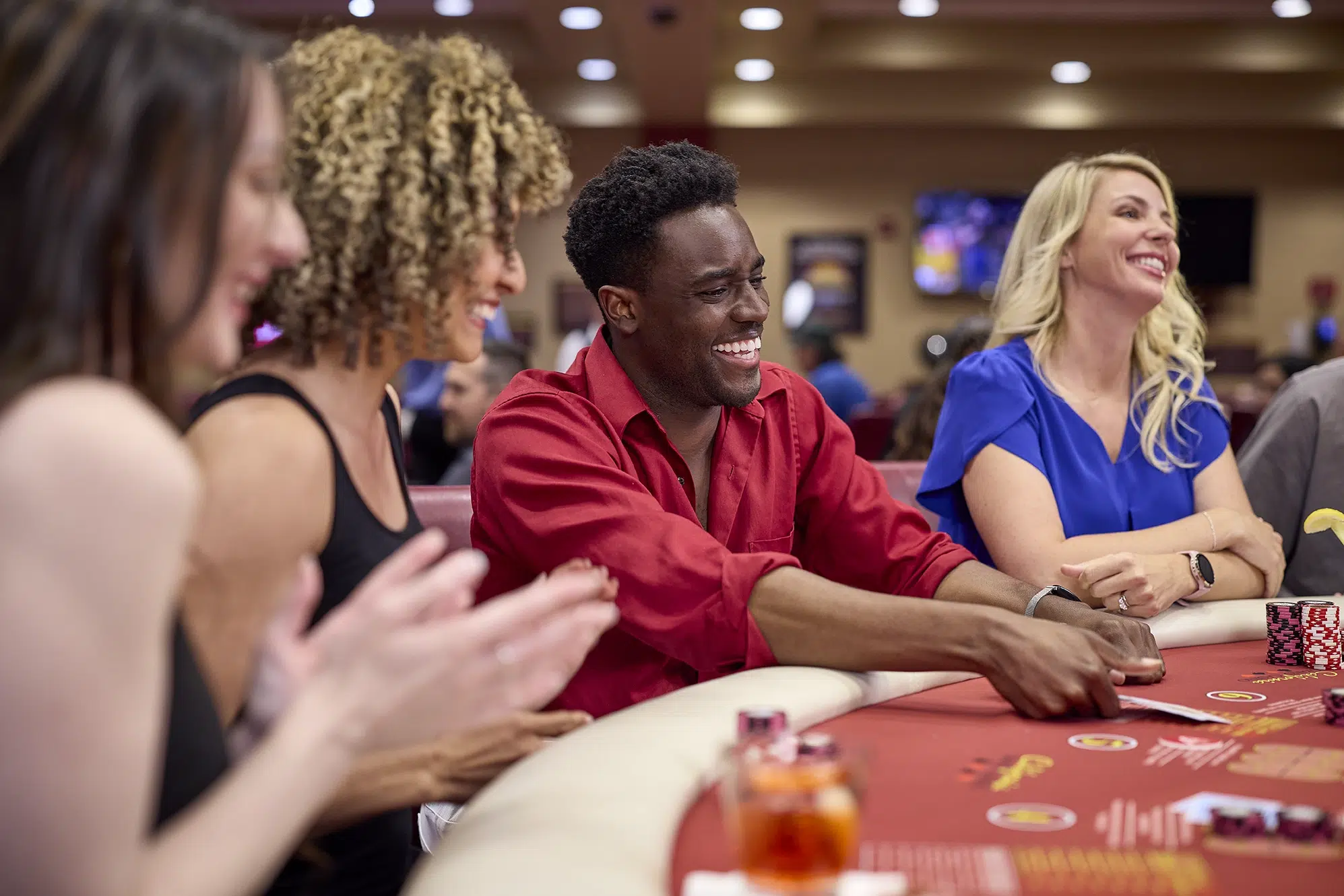 Excited group of players at a poker table in California Grand Casino, showcasing the fun of learning and playing with different poker hand combinations