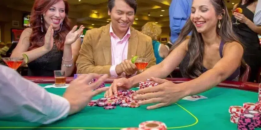 Smiling poker players at California Grand Casino celebrating a big win with stacks of chips on the table
